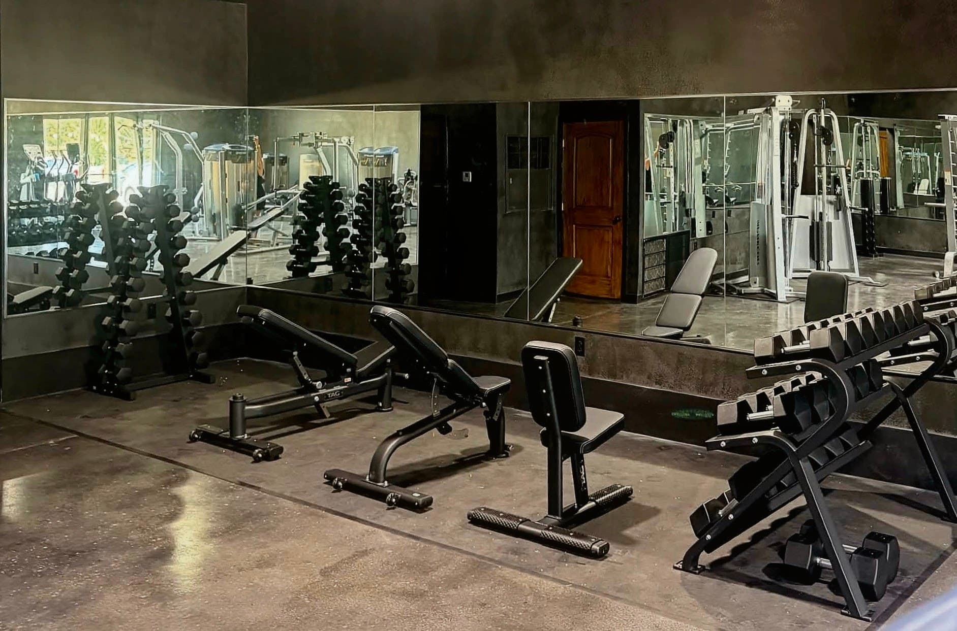 Southern Iron Fitness weight floor with benches, dumbbells, mirrors, and cable equipment